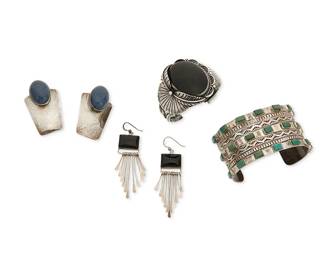 356
A group of Southwest silver jewelry
Late 20th century
Four works:

Anthony (Tony) Aguilar (1919-2002; Kewa)
Stamped: AT [conjoined] / Sterling
A chunky Santo Domingo Pueblo sterling silver cuff with row-set rectangular turquoise and multiple stamped bands
7 3/8" inner C x 1 5/8" H

A group of Native American jewelry
Each marked for maker/shop; two marked for sterling
Three works comprising a three-wire cuff with central set onyx and applied silver feather motifs, a pair of Michael Nez Navajo/Diné earrings with set blue stone cabochons, and a pair of Nakai (shop) set onyx earrings with silver dangles, 5 pieces
Cuff: 6" inner C x 2" H; earrings: 2 7/8" H and 2" H

6 pieces total
186.5 grams gross
Estimate: $500 - $700