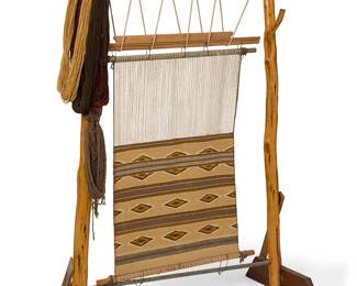 172
A Navajo textile loom
Mid-20th century, Diné
The loom on natural wood standards with trestle supports, with a partially woven Chinle-style textile, together with two framed photographs of a Navajo weaver in front of the loom
3 pieces
Loom: 70.5" H x 47.5" W x 28" D
Estimate: $400 - $600