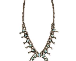 306
A Southwest silver and turquoise squash blossom necklace
Mid-20th century
Unmarked
Featuring a delicate two-wire sterling silver naja with set turquoise and silver feather and flower overlay, with ten matching blossoms, all suspended from silver beads and with an additional bead spacer, 2 pieces
24" L x 2 3/4" H; spacer: 4 1/2" L
96.1 grams gross
Estimate: $400 - $600