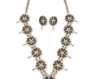 305
A Navajo sterling silver wedding basket "squash blossom" necklace
Late 20th century
Stamped: M / Sterling
A squash blossom-style necklace with a wedding basket pendant of mixed metal overlay and set turquoise, suspended by a double strand of silver beads and with ten basket "blossoms," together with a pair of matching earrings, 3 pieces
Necklace: 26.5" L x 2 7/8" H; earrings: 1 1/2" H
107.2 grams gross
Estimate: $600 - $800