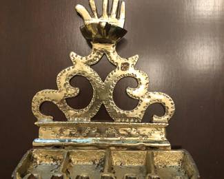 Antique brass Hanukkah lamp, 6” w x 5” h. Featuring the hamsa or the open hand, representing the five Pentatuchal books of the Bible invoked against the evil eye. Sicily 15th or 16th century, $1,000