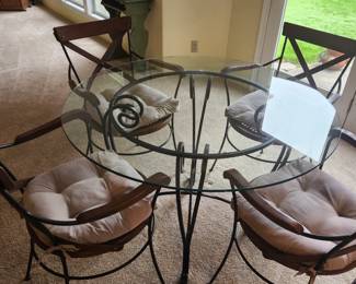 Wrought Iron and Glass Table with Four Wrought Iron with Woven Seats Chairs and Cushions. 