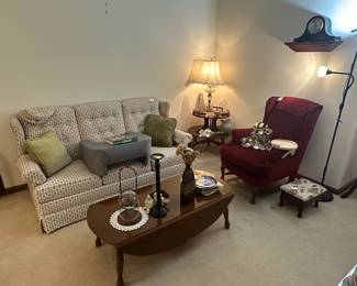 Hide-a-bed couch, dropleaf coffee table, maroon armchair, mantel clock, two-tiered round table