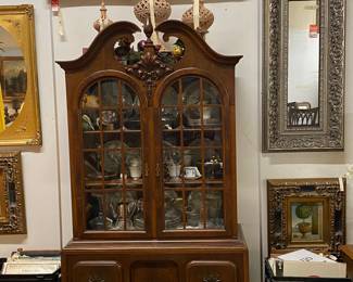 China cabinet topped with cut out terracotta lanterns, crystal and Lenox china inside
