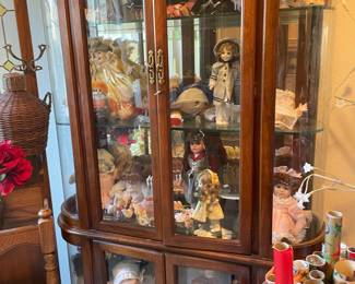 Rounded glass storage cabinet filled with collectible dolls