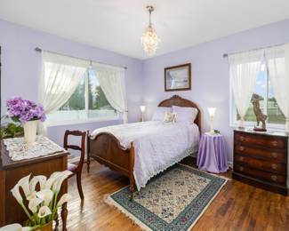 Bed and vanity set, brass large vase with lilies, dresser under the window, wool rug, vase & flowers, lace runner