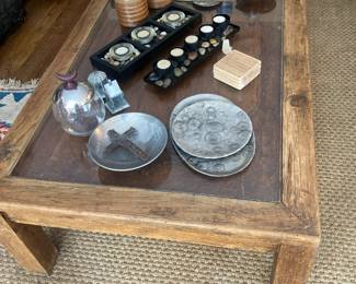Rustic wood coffee table with glass top over carved wood underneath, accessories