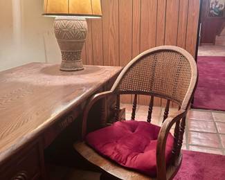 Wood office desk with organizational drawers and swiveling wood roller chair