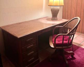 Wood office desk with organizational drawers and swiveling wood roller chair