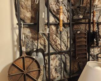 Cast iron items & more on wall in living room behind stove 