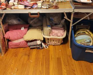 More bedding & pictures underneath table with collectibles