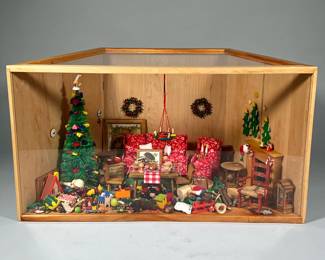 CHRISTMAS DOLLHOUSE DIORAMA | Miniature dollhouse diorama displaying Christmas figures, miniatures, etc. in a cozy room with a fireplace in a trapezoidal shadow box, with miniatures including copper andirons, a Christmas tree, sofa and matching armchair, Christmas wreaths, wall sconces, miniature toys, framed art, etc. - h. 11.5 x w. 23 x d. 13 in