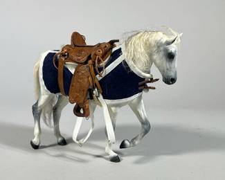 MINIATURE SADDLE & HORSE FIGURINE | White horse figurine with blue coat and a detailed tooled leather miniature saddle signed "Fly" and dated '82 - h. 6.5 x w. 2.5 x l. 7 in