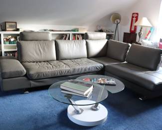 Modern large  leather sectional that provides plenty of seating for family and friends.  On closer inspection, however, you’ll find that there’s more to it than meets the eye. An adjustable arm rest can be tilted in multiple positions for a variety of uses and the two removable headrests can be moved to any seat as needed. The most impressive mechanism is carefully  hidden in the back cushions.  Sliding them back converts the standard seat depth into a deeper one to accommodate more casual lounging and taller guests.