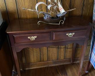 Vintage metal pirate ship model on console table.