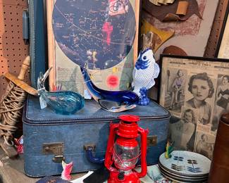 Vintage suitcases, ads from the early 1900s, vintage pottery, and fish art glass.