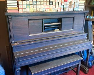 Antique player piano with music rolls and bench