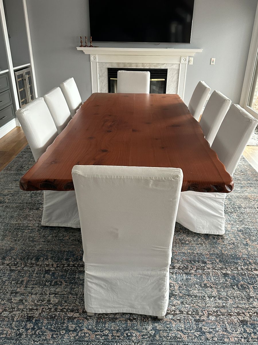 Custom hand-crafted live-edge Woodland Creek dining table; 8 Crate and Barrel white slip-covered dining chairs