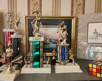 Bowling and dart trophies, Toledo lighthouse print, Rubick's cube, Thomas Kinkade print