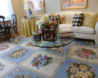 White sofa, lucite & glass top coffee table, skirted side table, bric-a-brac, needlepoint area rug