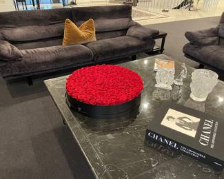 Another view of the Italian custom upholstered seating: couch by B. B. Alanda (back upper portions adjusts to resting position) with colored mohair pillow, black marble cocktail table (66" square x 17"), Chanel book, Lalique, Baccarat - golfer (9"), and Venus et Fluer - silk rosebuds
