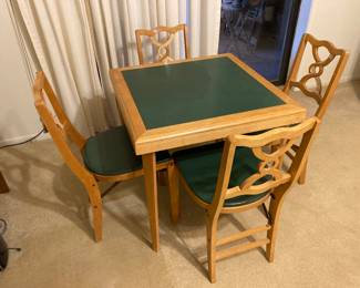 This is an an antique folding table with four chairs.