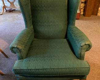 One of two green upholstered wingback chairs.