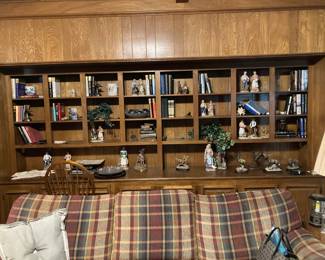 The huge bookcase in the den is full of figurines, statues, books, and vintage knickknacks.