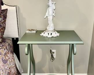 Close-up of green painted side table with figural lamp