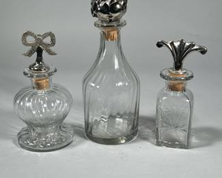 (3pc) GLASS BOTTLES WITH PEWTER STOPPERS | Decorative glass bottles with figural pewter stops. - h. 9 in (tallest)