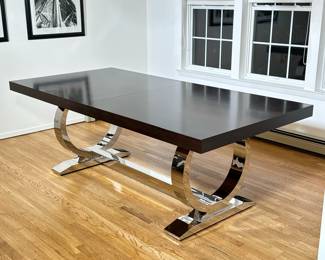 Z GALLERIE CHROME & WOOD DINING TABLE | A contemporary dining table from Z Gallerie featuring a rectangular wood veneer top in a dark espresso finish. The table is supported by two sculptural chrome pedestal bases in a circular ring design, creating a modern aesthetic. The materials combine polished chrome with the warmth of the wooden top, making it a versatile centerpiece for dining rooms. Includes 1-20 in. leaf. - 