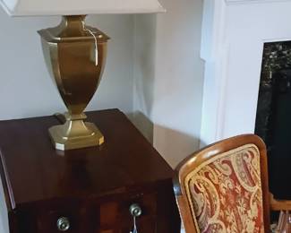 Two drawer stand, upholstered chair, pair of brass lamps
