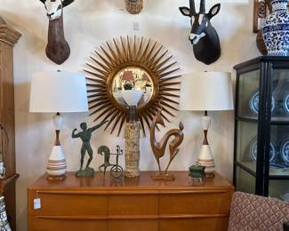Heywood Wakefield triple dresser, Pair vintage pottery and teakwood lamps, Carved giltwood sunburst mirror, Pair Art Deco armchairs, Trio of animal trophy heads, Bronze Weinberg charioteer.