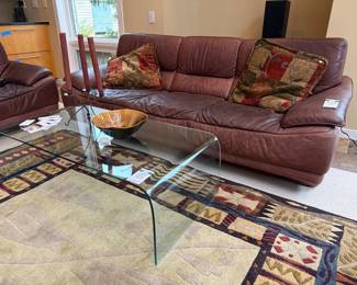 Curved glass curved table, candle holder, Bill campbell style crystaline bowl, Giorgio collection leather sofa, decorative pillows