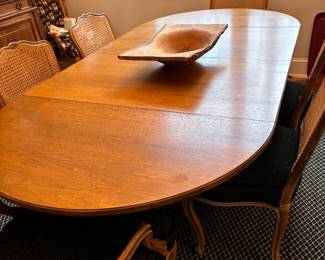 Dining table with six wood and cane chairs and two leaves.