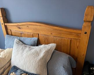 Closer view of the headboard on the full-size pine bed with mattress and box spring.