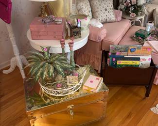 Gold trunk, trays, shabby chic pink chair and ottoman, white side table, kids books, pillows, wicker coat stand, Kate Spade handbag, Hollywood Regency decor