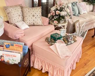 Gold trunk, trays, shabby chic pink chair and ottoman, white side table, kids books, pillows, wicker coat stand, Kate Spade handbag, Hollywood Regency decor