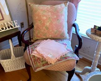 Pink fabric armchair, pillows, white wicker baskets and furniture
