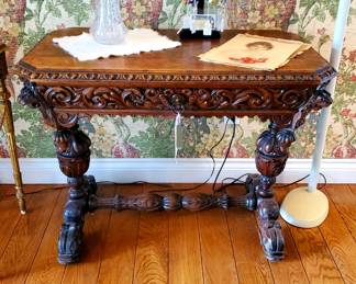 19thc ornately Carved table with fish serpent feet and lion heads on the 4 corners. It also has a draw.