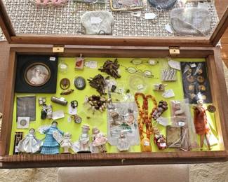 Lots of littles in Display case. Miniature Portrait painting, Huge Amber necklace, mini porcelain dolls, sterling thimbles and more.