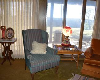Wing back chair between 2 beautiful tables.