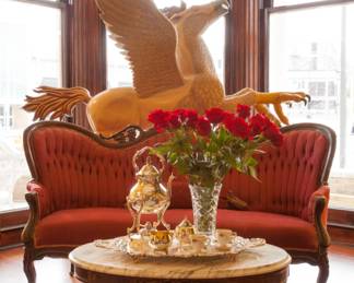 Main Parlor - Hand carved "Hippogriff" Carousel Creature, Maroon Victorian Couch, Marble Coffee Table 