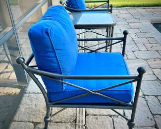 Four black metal outdoor chairs - two have solid blue upper cushions, and two have blue & white striped upper cushions. Three matching metal tables - one circular, one square, and one rectangular.