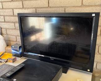 Electronics Setup
A Vizio flat-screen TV paired with a DVD player and remote, alongside other electronics and small accessories—ideal for upgrading your entertainment system.