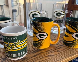 Green Bay Packers NFL memorabilia: beer steins, coffee mugs, tire cover, gnome, cutting board
