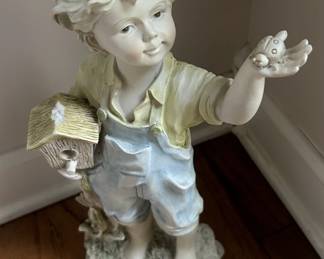 Boy in Blue Overalls holding a bird house Figurine