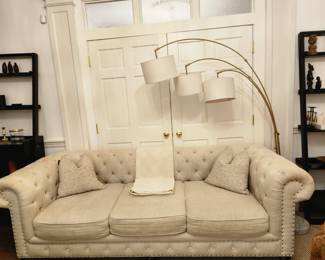 A set of identical ivory linen sofas, West Elm lamp, wine shelf, book shelf.