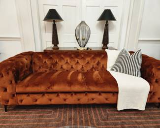 Tufted burnt orange sofa.