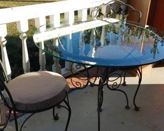 Vintage outdoor wrought iron bistro table with heavy glass top and two matching chairs